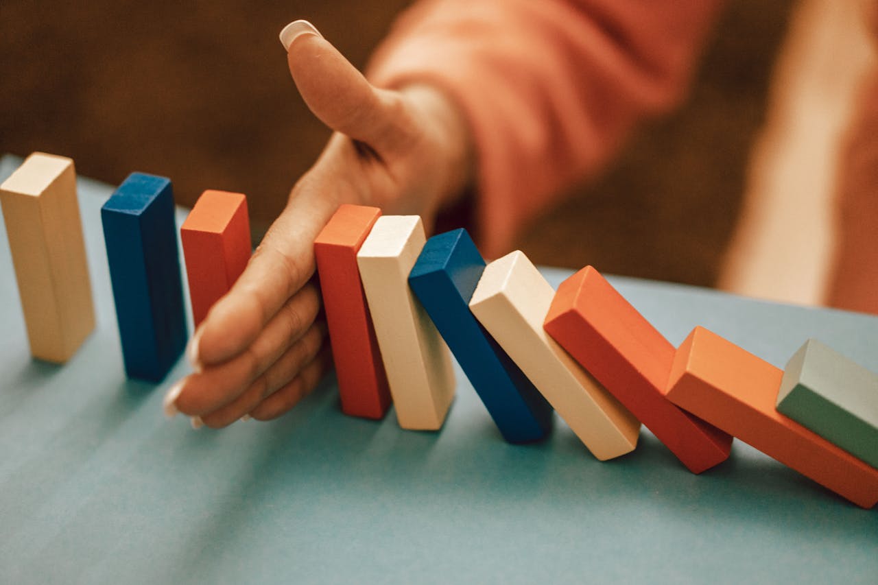 Mastering the First Impression: Your intriguing post title goes here A hand strategically stops falling blue and red domino blocks on a table.